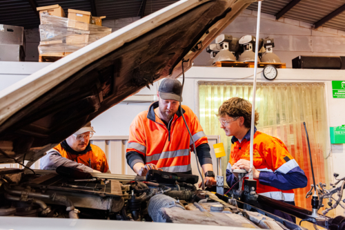 Male mechanics checking car engine in industrial workspace with digital diagnostics tool - Australian Stock Image