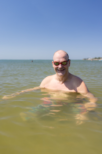 Male open water swimmer wearing goggles smiling in portrait - Australian Stock Image