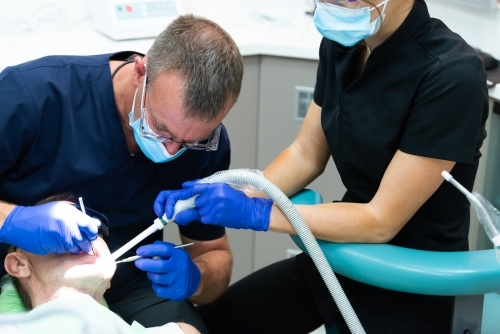 Male patient having teeth cleaned at dentist - Australian Stock Image