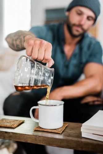 Male pouring coffee into a cup at home - Australian Stock Image