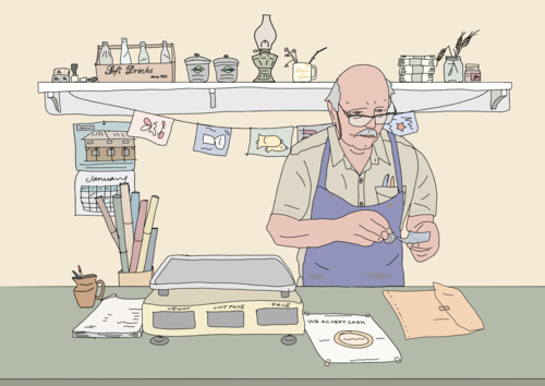 Male shopkeeper wearing blue apron and glasses standing behind counter of old shop - Australian Stock Image