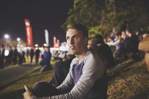 Male spectator sitting on grass at an event