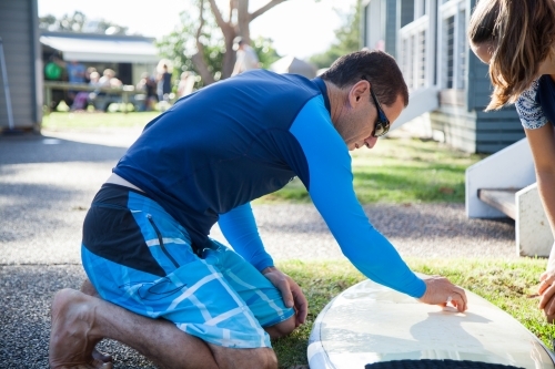Male surfer waxing new surfboard with wax - Australian Stock Image