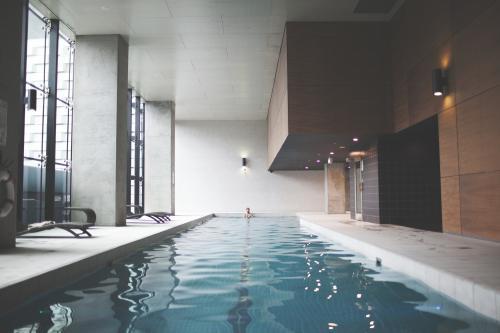 Male swimmer at far end of contemporary indoor lap pool - Australian Stock Image