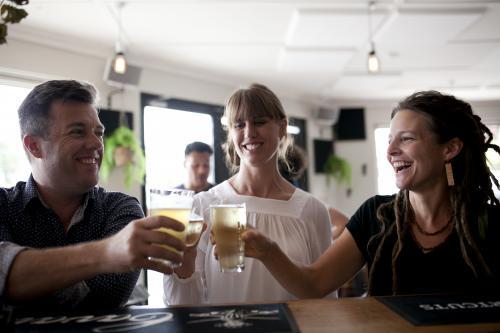 Man and two women raising glasses at local craft beer bar - Australian Stock Image