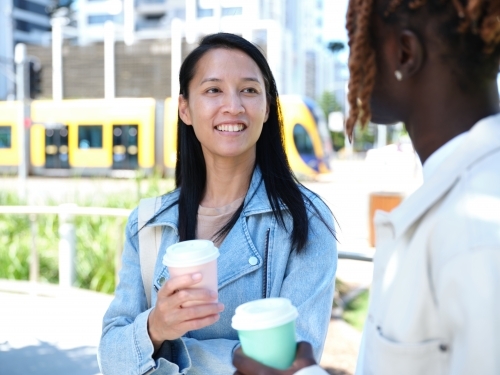 Man and woman drinking from coffee cups and having a conversation - Australian Stock Image