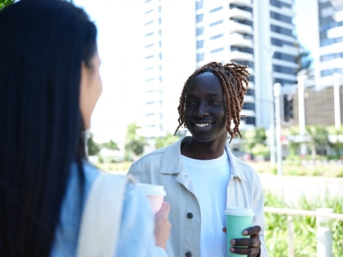 Man and woman drinking from coffee cups and having a conversation - Australian Stock Image