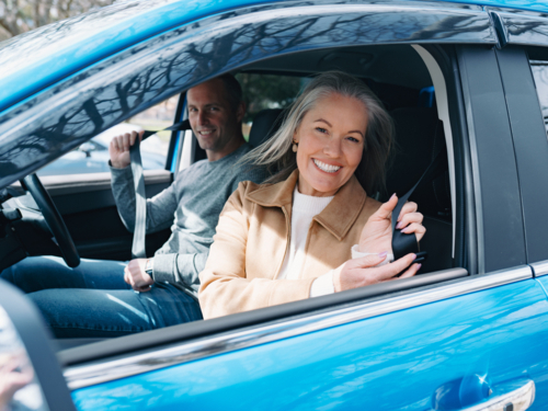 Man and woman fastening seatbelt inside blue car - Australian Stock Image