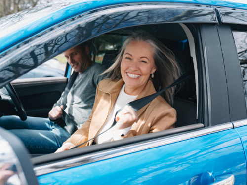 Man and woman fastening seatbelt inside blue car - Australian Stock Image