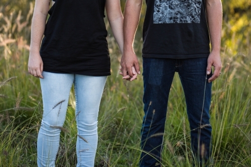 Man and woman holding hands in long grass - Australian Stock Image