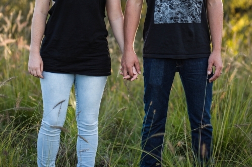 Man and woman holding hands in long grass