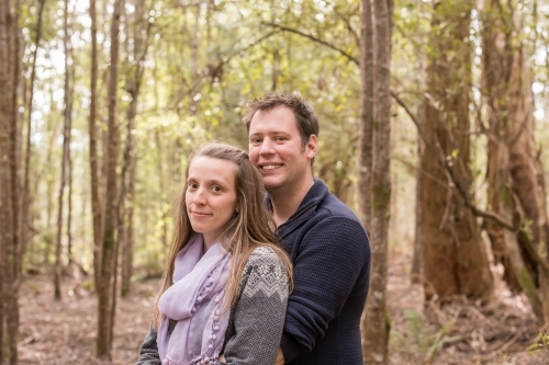 Man and woman in an embrace standing in the forest - Australian Stock Image