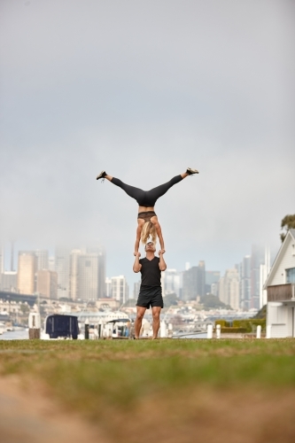 Man and woman practising acrobatics with city in background - Australian Stock Image