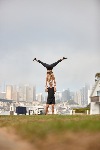 Man and woman practising acrobatics with city in background