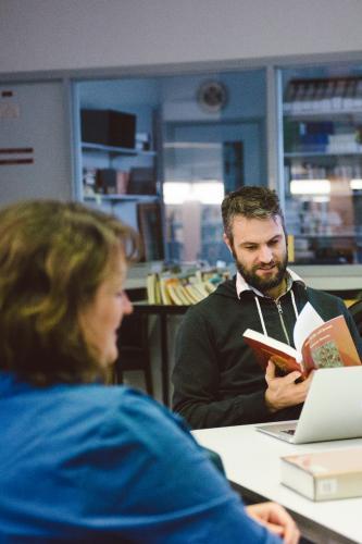 Man and woman reading books in the university library - Australian Stock Image
