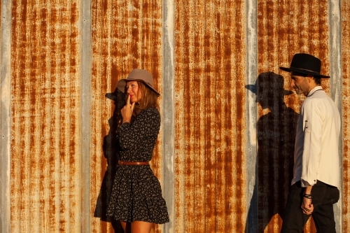 Man and woman standing against rusted iron wall - Australian Stock Image