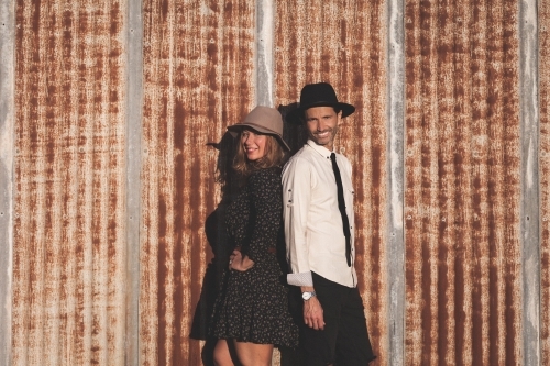 Man and woman standing back to back against rusted iron wall - Australian Stock Image