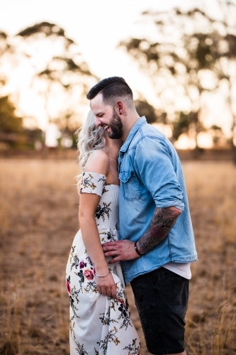 Man and woman standing together sharing secrets laughing - Australian Stock Image