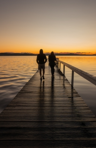 Man and Woman walking on Jetty at Sunset