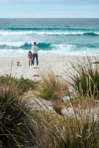 Man boy and girl looking at crashing waves on beach - Australian Stock Image