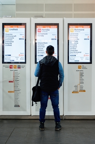 Man checking train timetable at station - Australian Stock Image