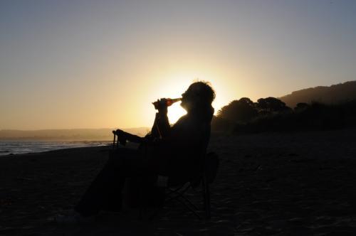 Man drinking from a bottle, silhouetted against low light sky - Australian Stock Image