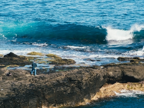 Man fishing on the rocks - Australian Stock Image