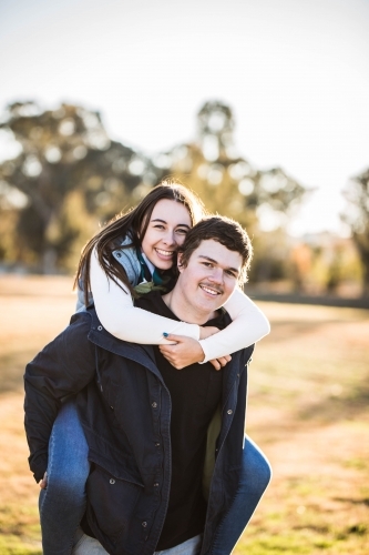 Man giving girlfriend piggy back ride smiling - Australian Stock Image