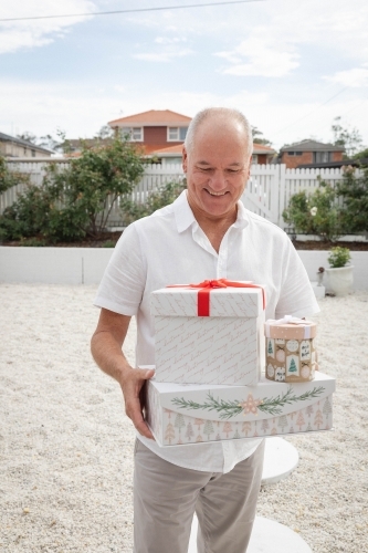 Man holding Christmas presents in front yard - Australian Stock Image