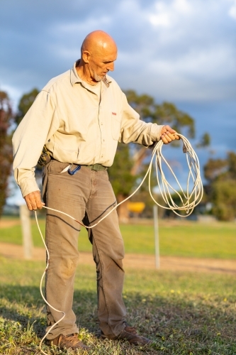 man holding electrical extension cord like a lasso - Australian Stock Image