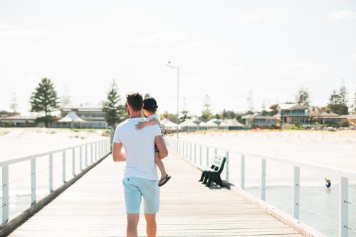Man holding onto toddler walking on a jetty - Australian Stock Image