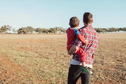 Man holding toddler walking in a paddock - Australian Stock Image