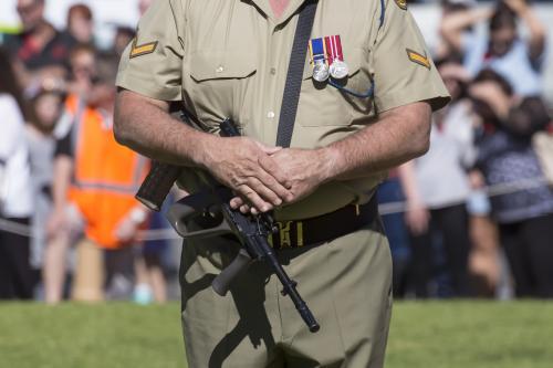 Man in army uniform with rifle participating in ANZAC Day ceremony - Australian Stock Image