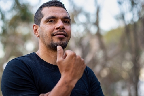 man in black with hand in fist up towards face - Australian Stock Image