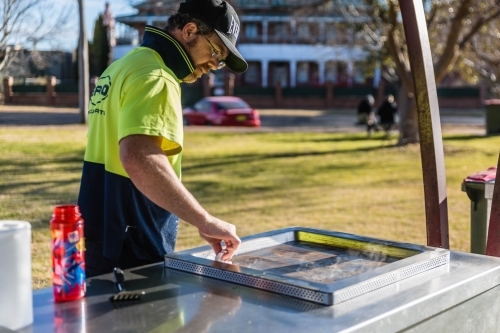 Man in hat cleaning barbecue - Australian Stock Image