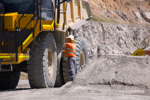 Man in high visibility clothes checking the sides of the dump truck. - Australian Stock Image