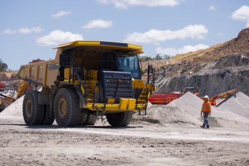Man in high visibility clothes walking towards the dump truck. - Australian Stock Image
