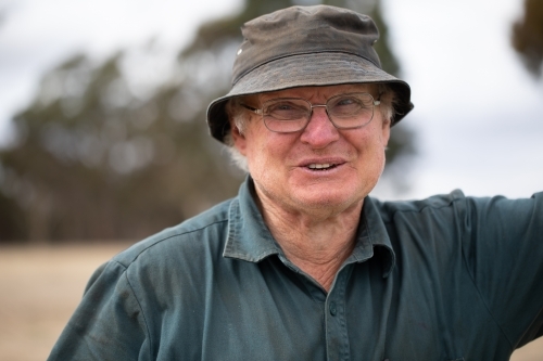 man in his sixties wearing workwear happily glancing away - Australian Stock Image
