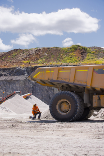 Man in workwear checking the back end of the hauler dump truck on mine site - Australian Stock Image