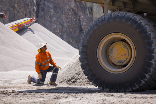 Man in workwear checking the back end of the hauler dump truck on mine site - Australian Stock Image