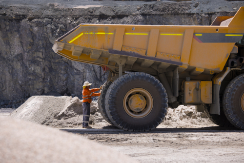 Man in workwear checking the back end of the hauler dump truck on mine site - Australian Stock Image