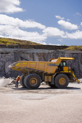 Man in workwear checking the back end of the hauler dump truck on mine site - Australian Stock Image