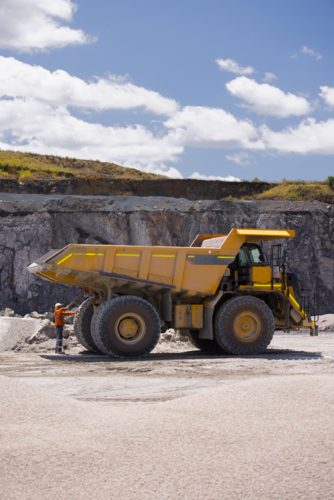 Man in workwear checking the back end of the hauler dump truck on mine site - Australian Stock Image