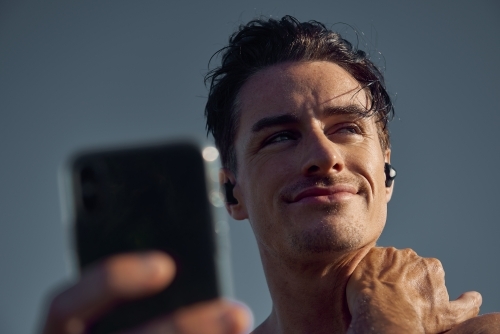 Man listening to music on phone while exercising - Australian Stock Image