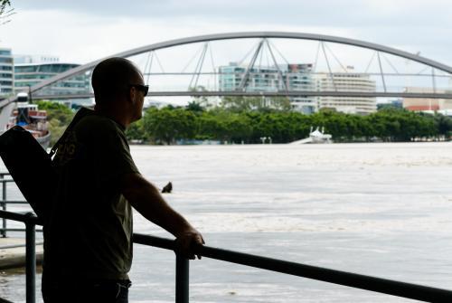 Man looking out on Flooded Brisbane River with Goodwill Bridge in background - Australian Stock Image