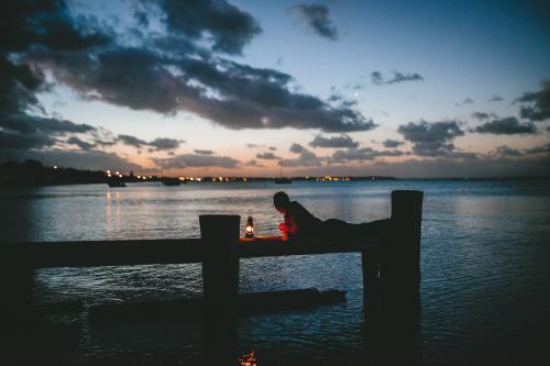 Man on old wooden jetty with lamp at dusk