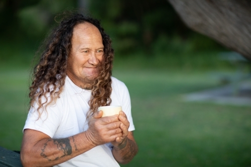 man outdoors in park holding cup in hands - Australian Stock Image