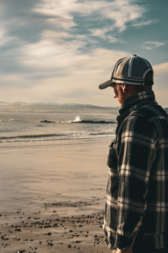 Man overlooking the ocean, wearing a cap - Australian Stock Image