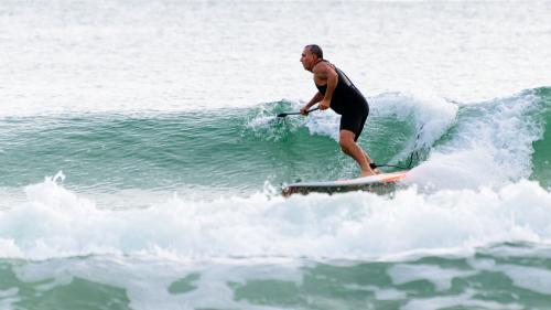 Man paddleboarding on waves - Australian Stock Image