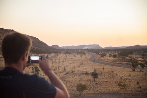 Man photographing outback landscape at dusk